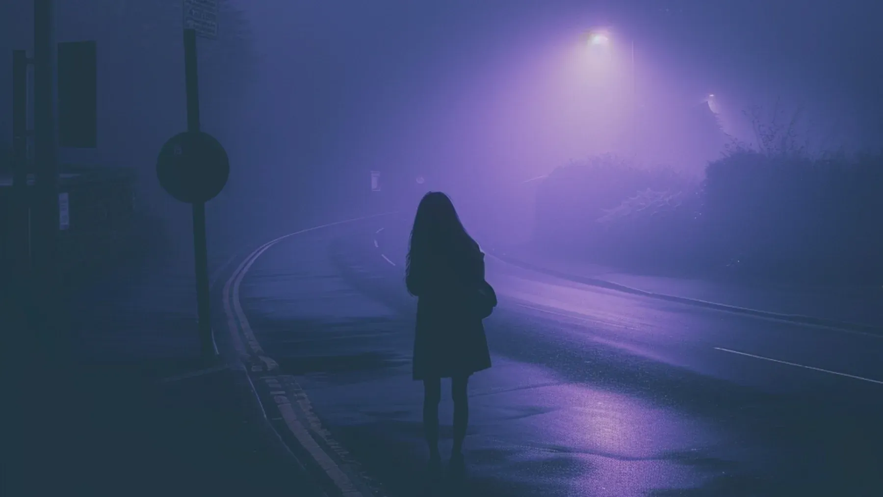 A lone figure stands on a fogbound road, carrying the isolation and uncertainty that remain after shared history becomes suspect.