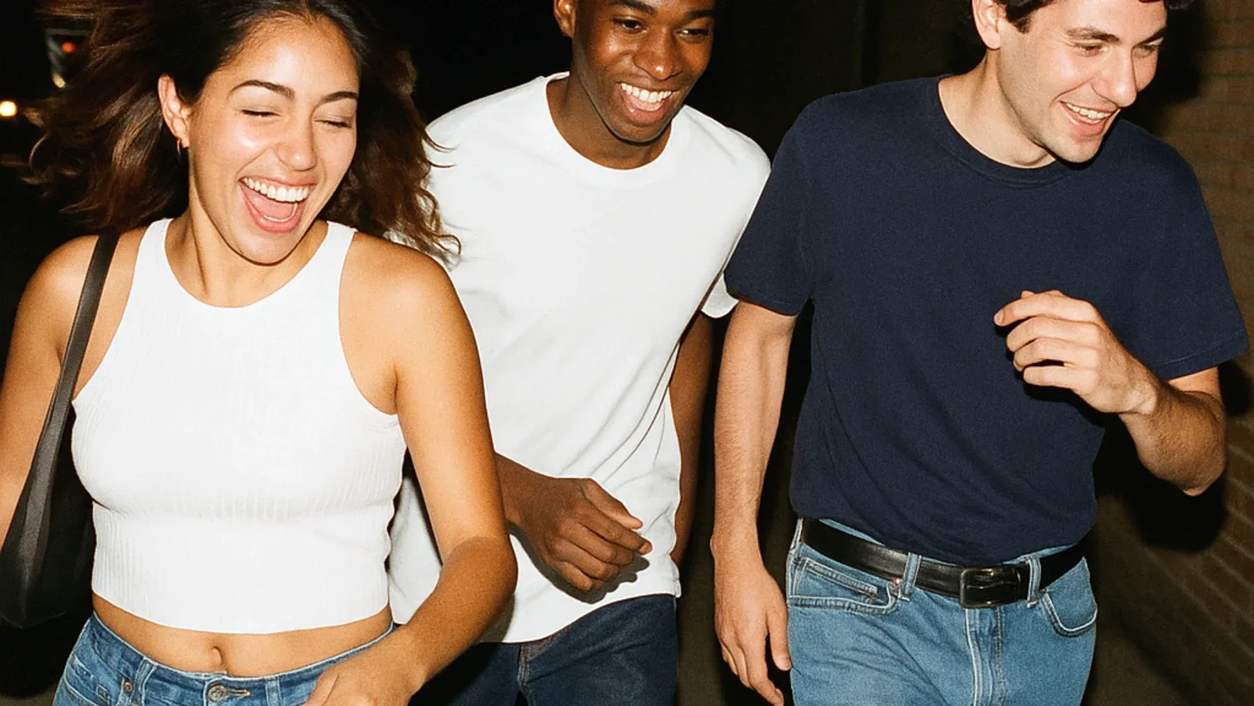 Three friends laugh together at night, giving the later betrayal a history of ordinary safety and shared life to damage.