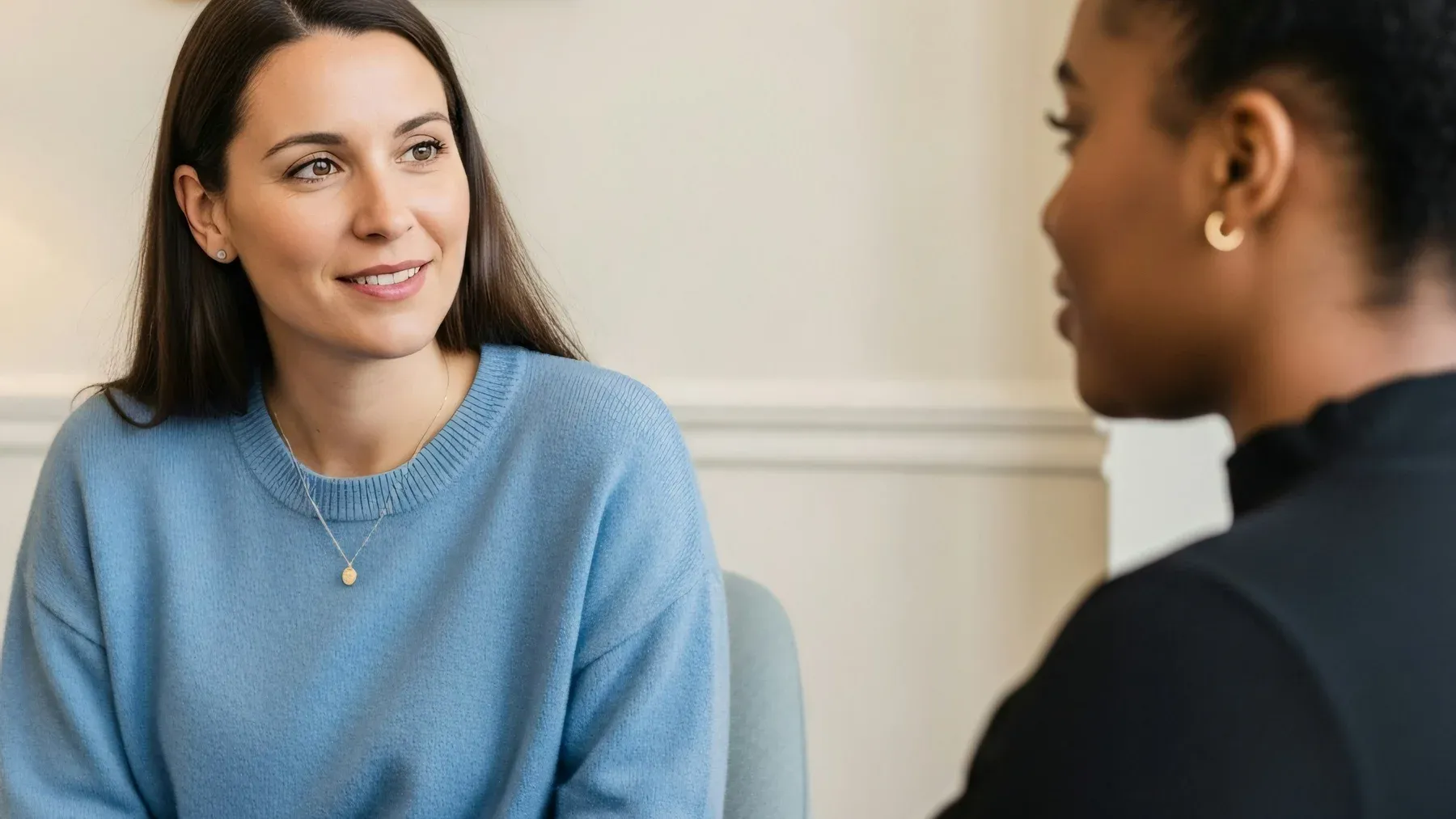 Two colleagues talk at eye level in a quiet room, showing support as a negotiated part of an ongoing reciprocal relationship.
