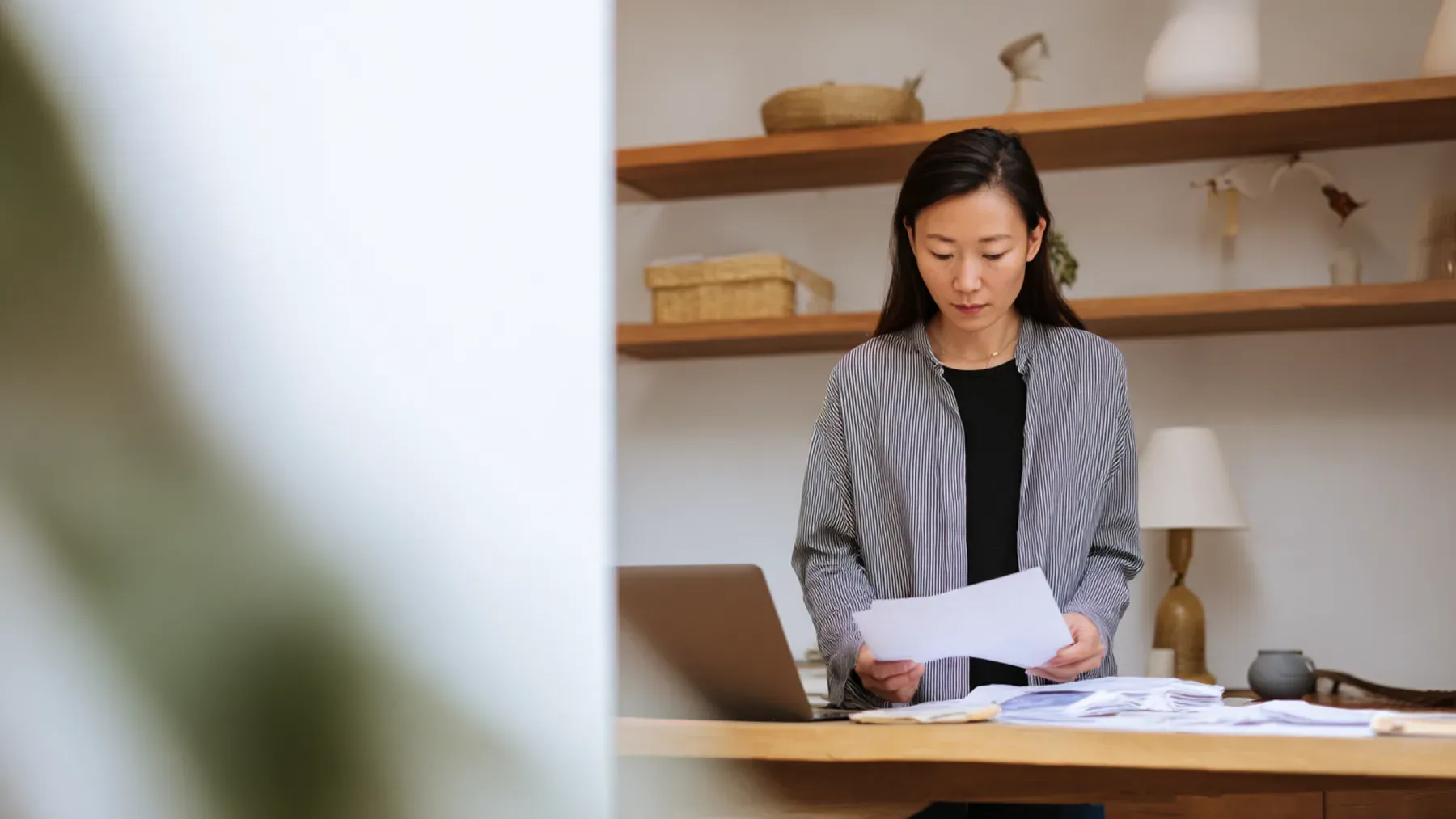 A woman comparing printed records at a desk before choosing an action that will expose her source.