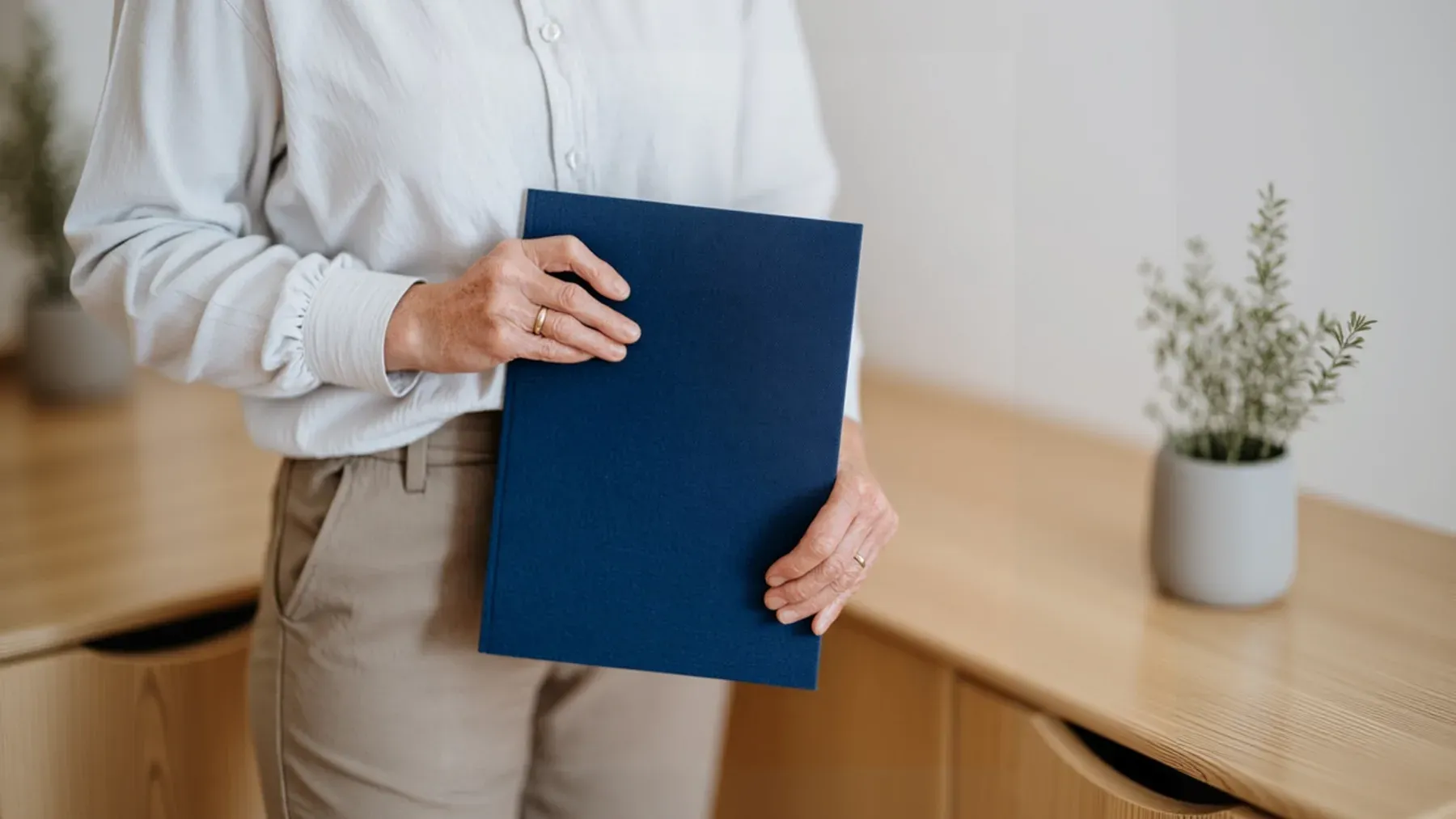 A person holds a blue document folder against neutral clothing, representing evidence that must pass from private control into another person's hands.