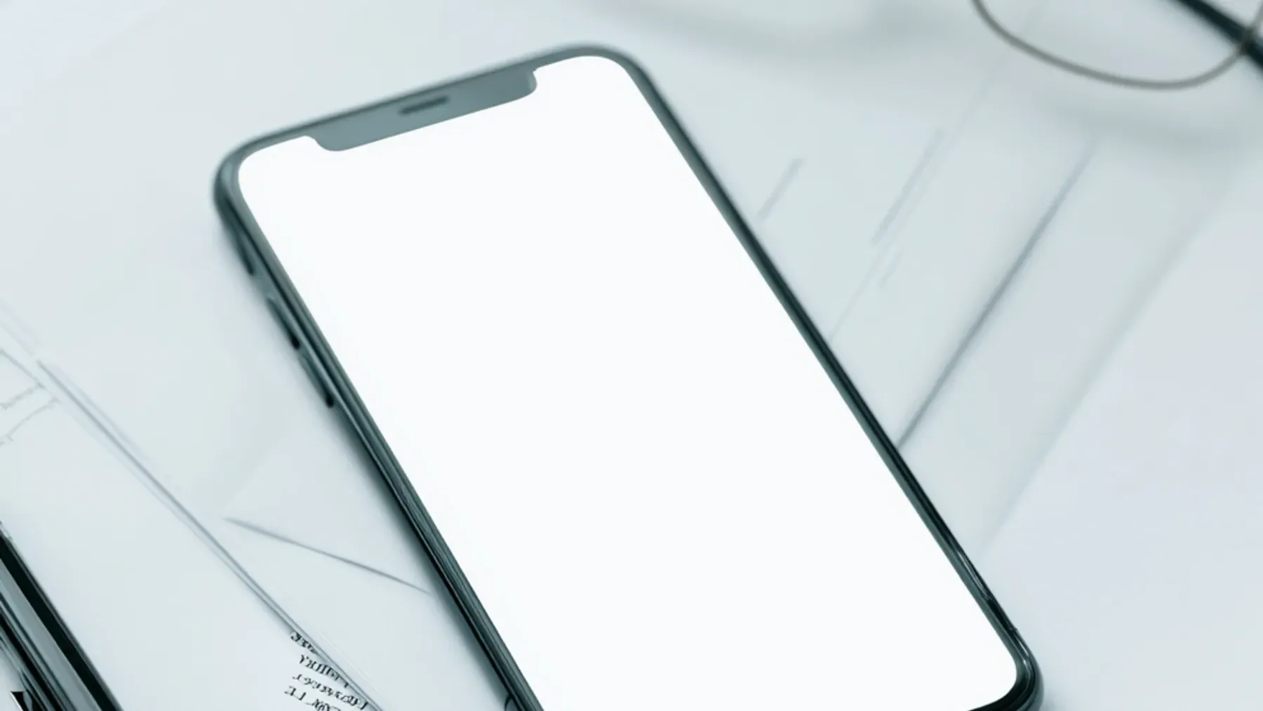 A blank phone rests beside papers and glasses, making the unanswered message a choice about channel, timing, and access.