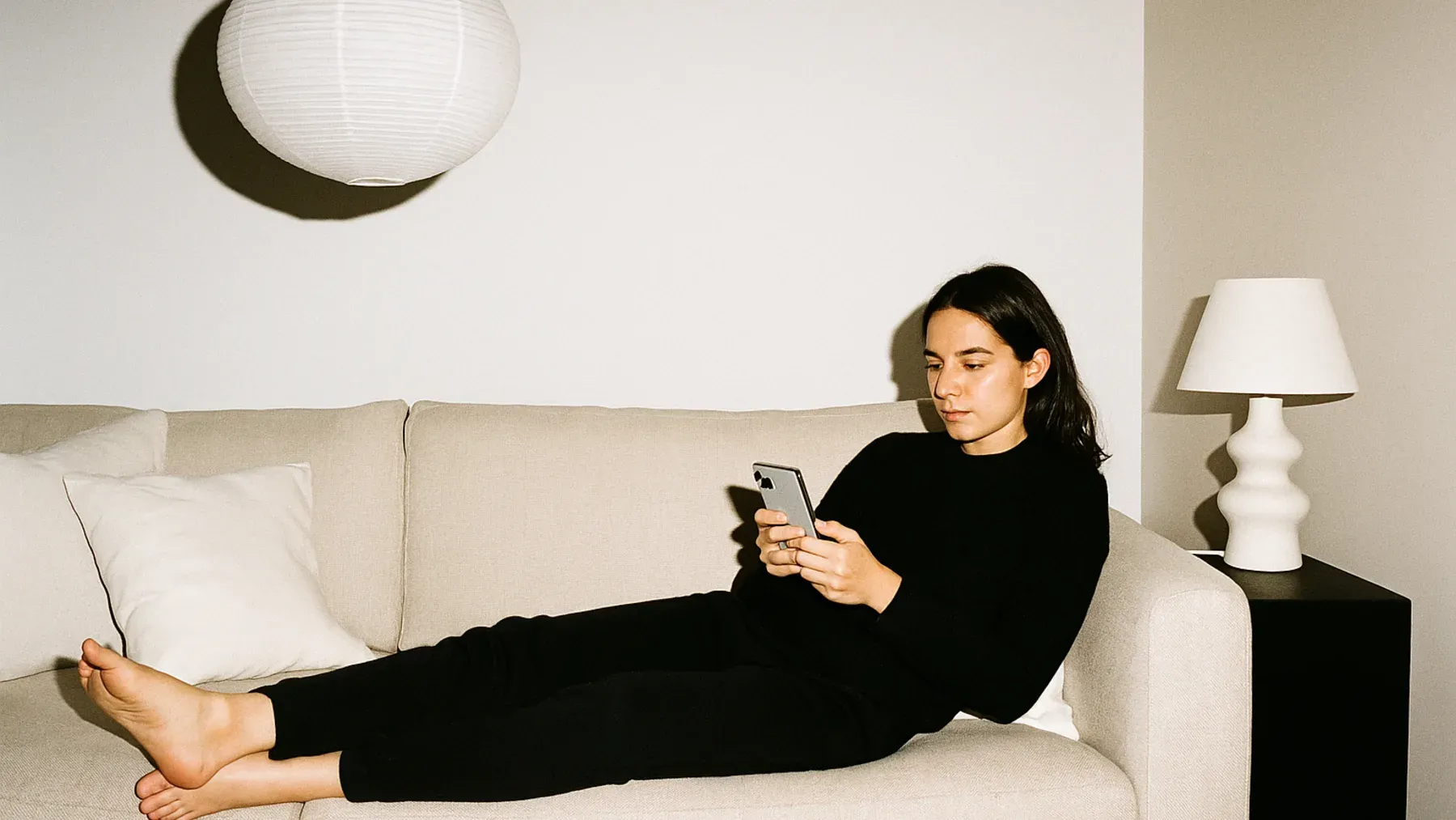 An adult daughter sits alone with a phone, showing how estrangement shapes ordinary choices long before a family confrontation begins.
