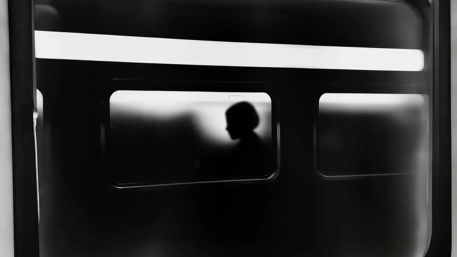 A silhouette visible through frosted glass, representing a captive whose presence is known while intention and usable information remain obscured.