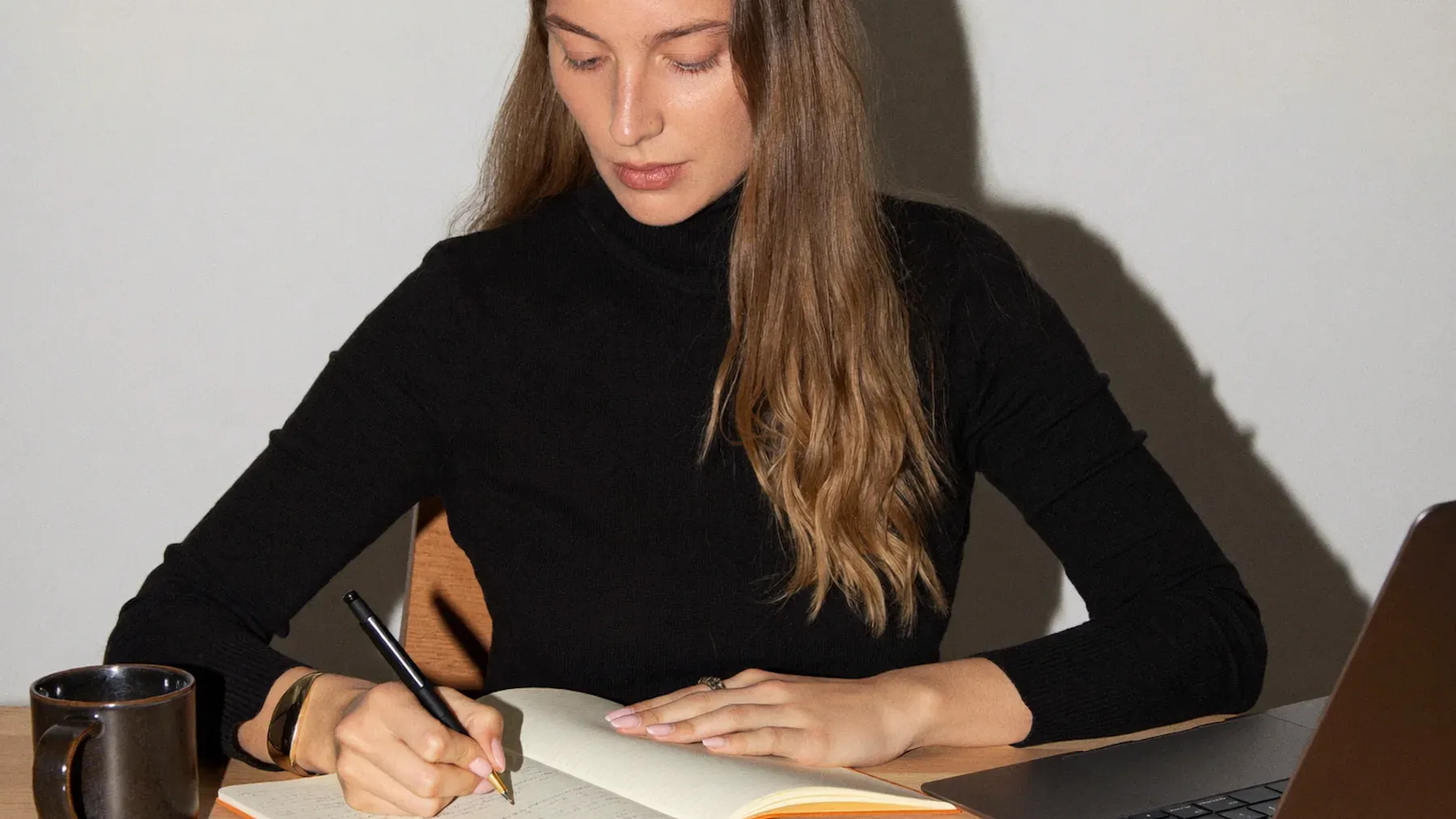 A writer revises beside a laptop, tracing where narrative access widens, narrows, and changes pressure across the scene.